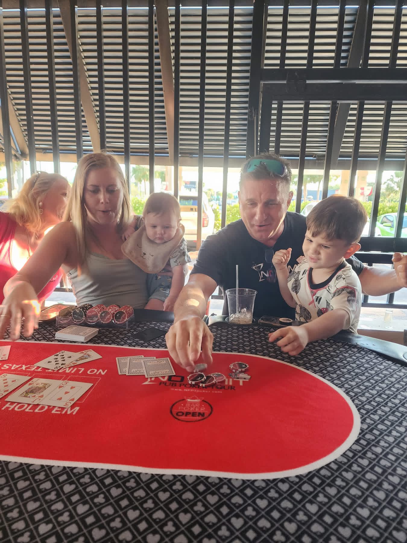 Guests gathered around a red poker table with cards and chips